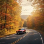 Autumn road trip through a colorful forest with a classic car